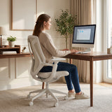 Woman working at a desk while seated in a white BIRCH ergonomic chair in a bright home office