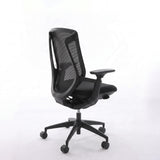 Black BIRCH ergonomic chair in rear three-quarter view showing its mesh back and five-wheel base