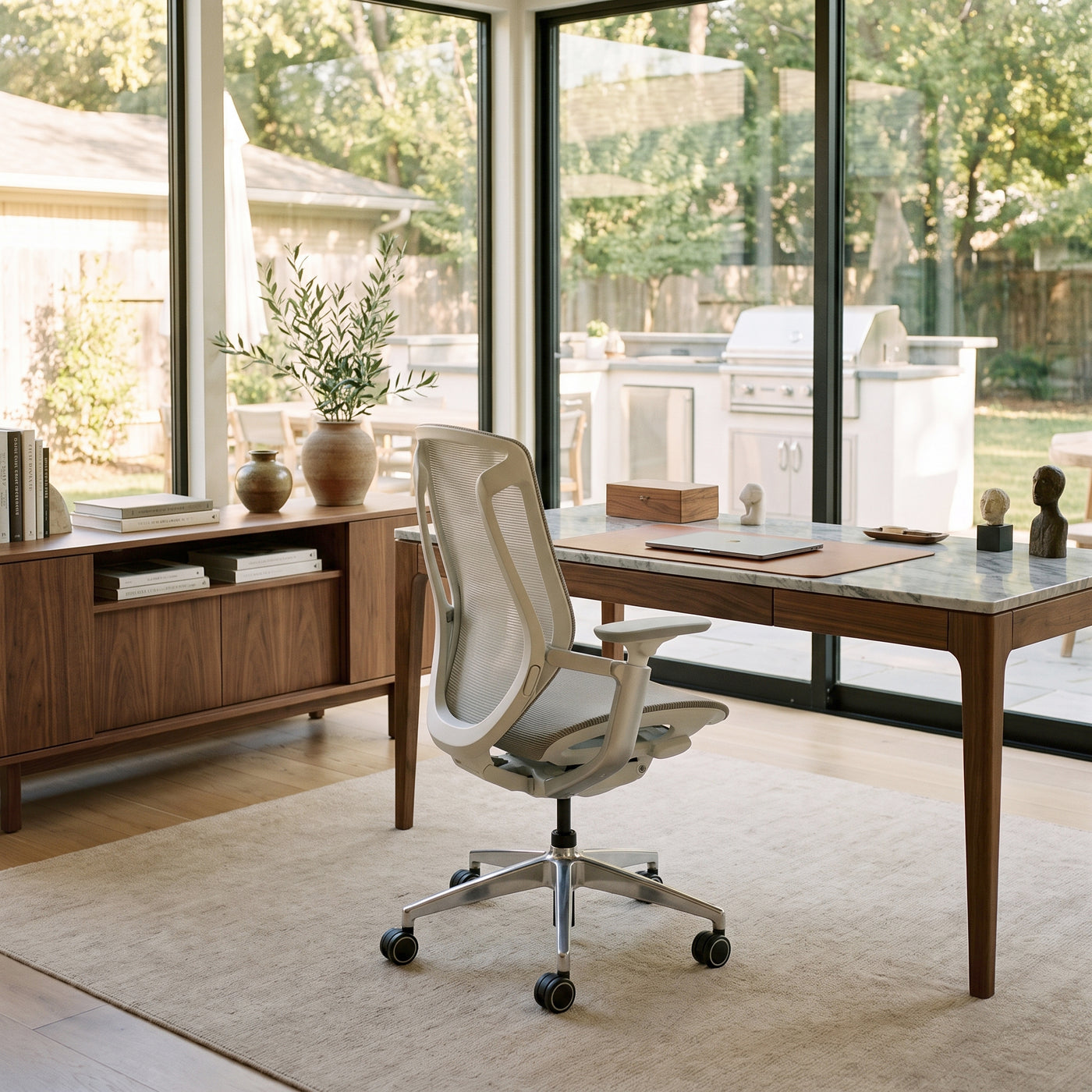 Grey BIRCH ergonomic chair at a wooden desk in a bright home office overlooking a patio